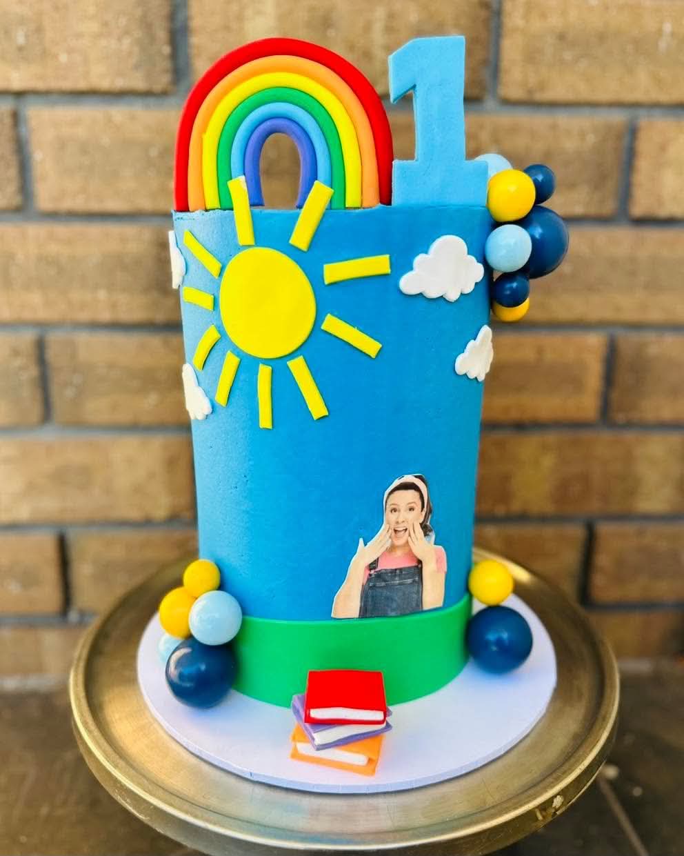 Blue sky themed 1st birthday cake with rainbow, sun, clouds and Wiggles Emma edible print